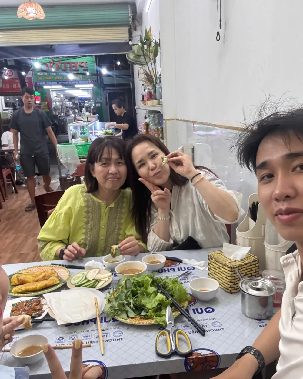 Guests sharing bánh xèo and fresh herbs at a local restaurant