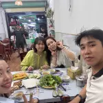 Guests sharing bánh xèo and fresh herbs at a local restaurant