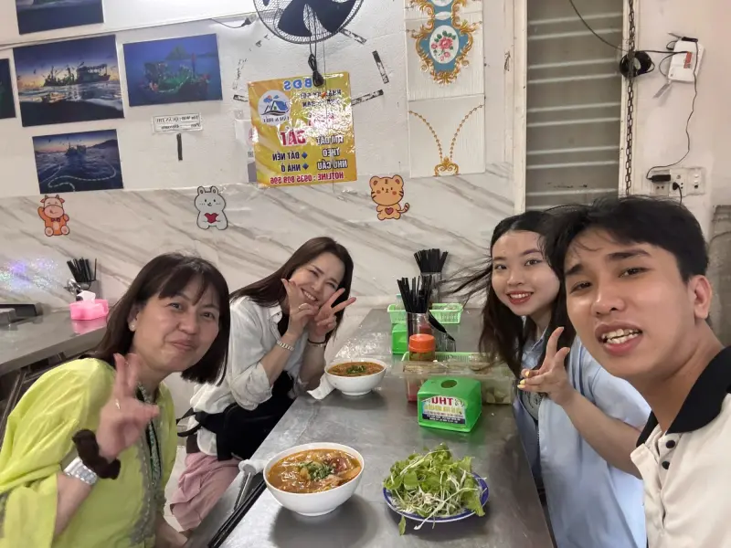 Guests with a bowl of mì Quảng and fresh herbs