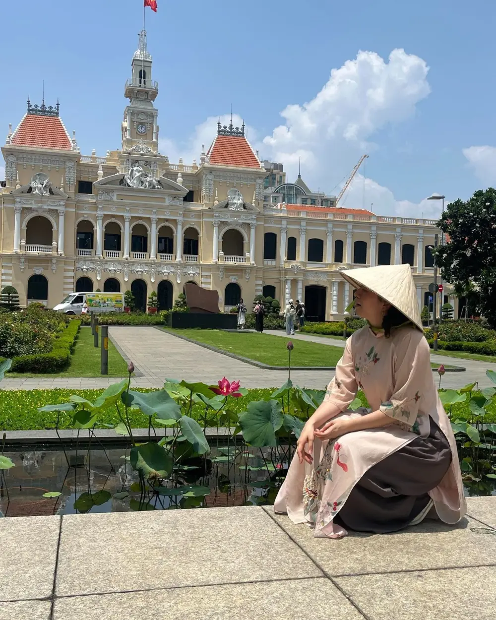A traveler in a conical hat in front of Saigon City Hall