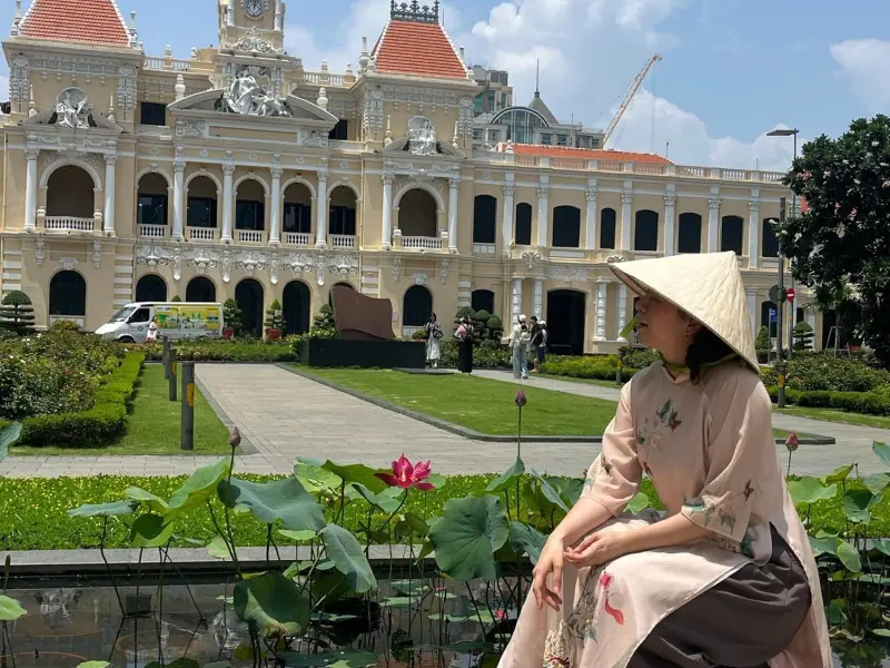 A traveler in a conical hat in front of Saigon City Hall