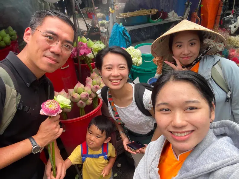 A family with lotus flowers at a Saigon flower market with their guides