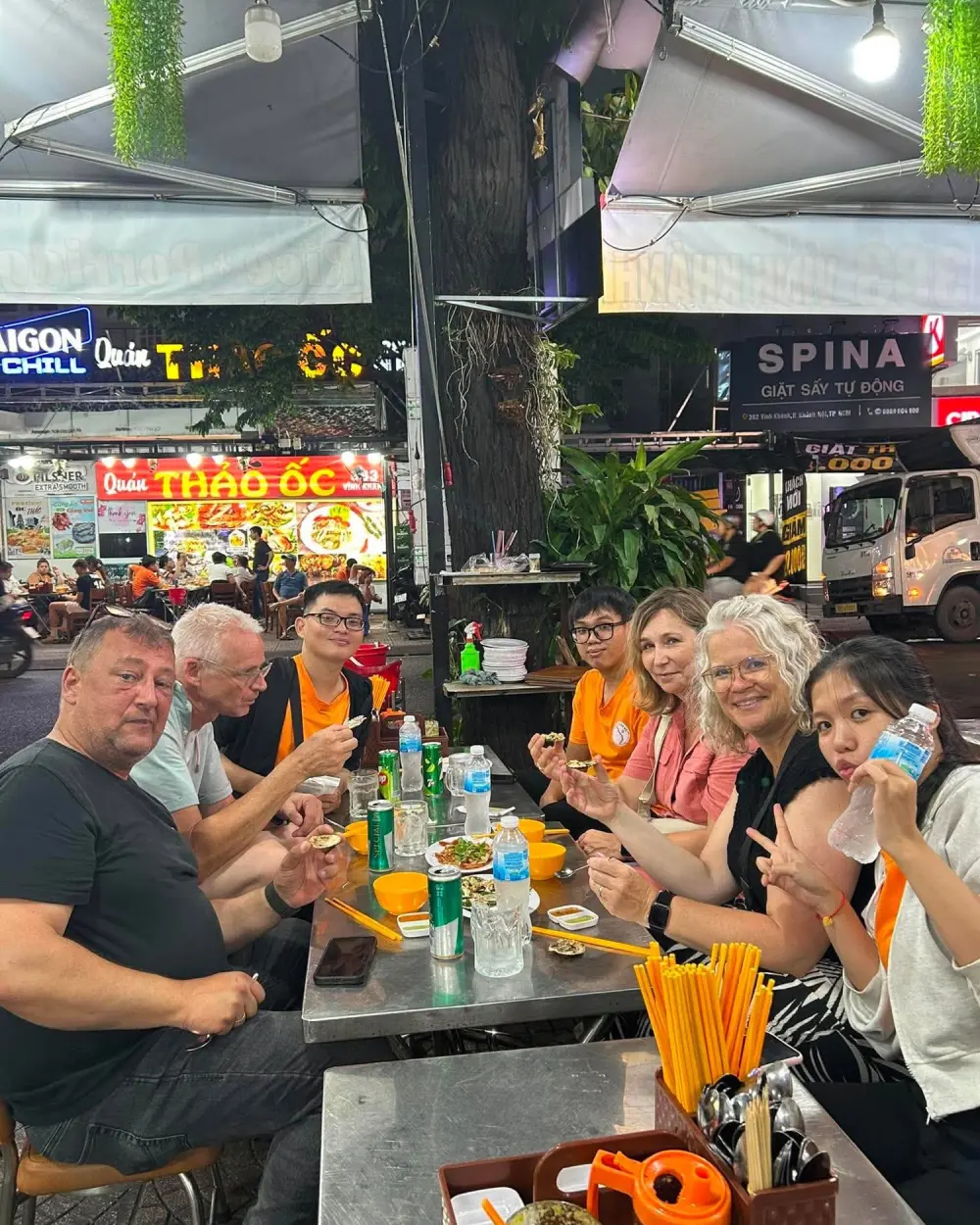 Guests sharing snails and drinks at a street food table in Saigon at night