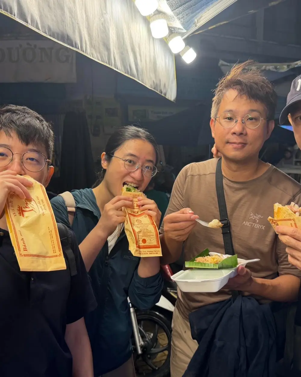 Guests eating bánh mì at a night food stall in Saigon